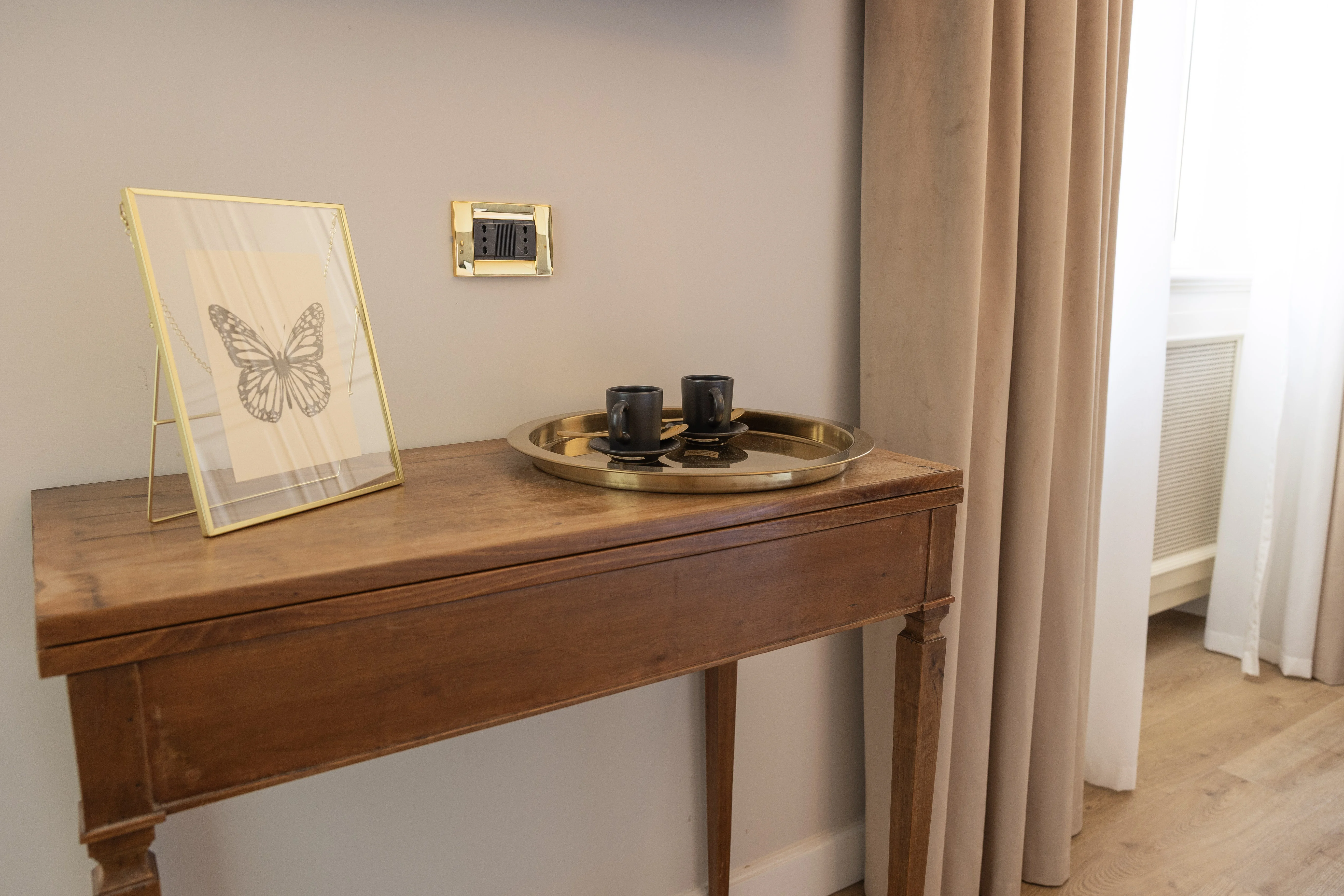 Console in legno antico con vassio dorato e tende beige