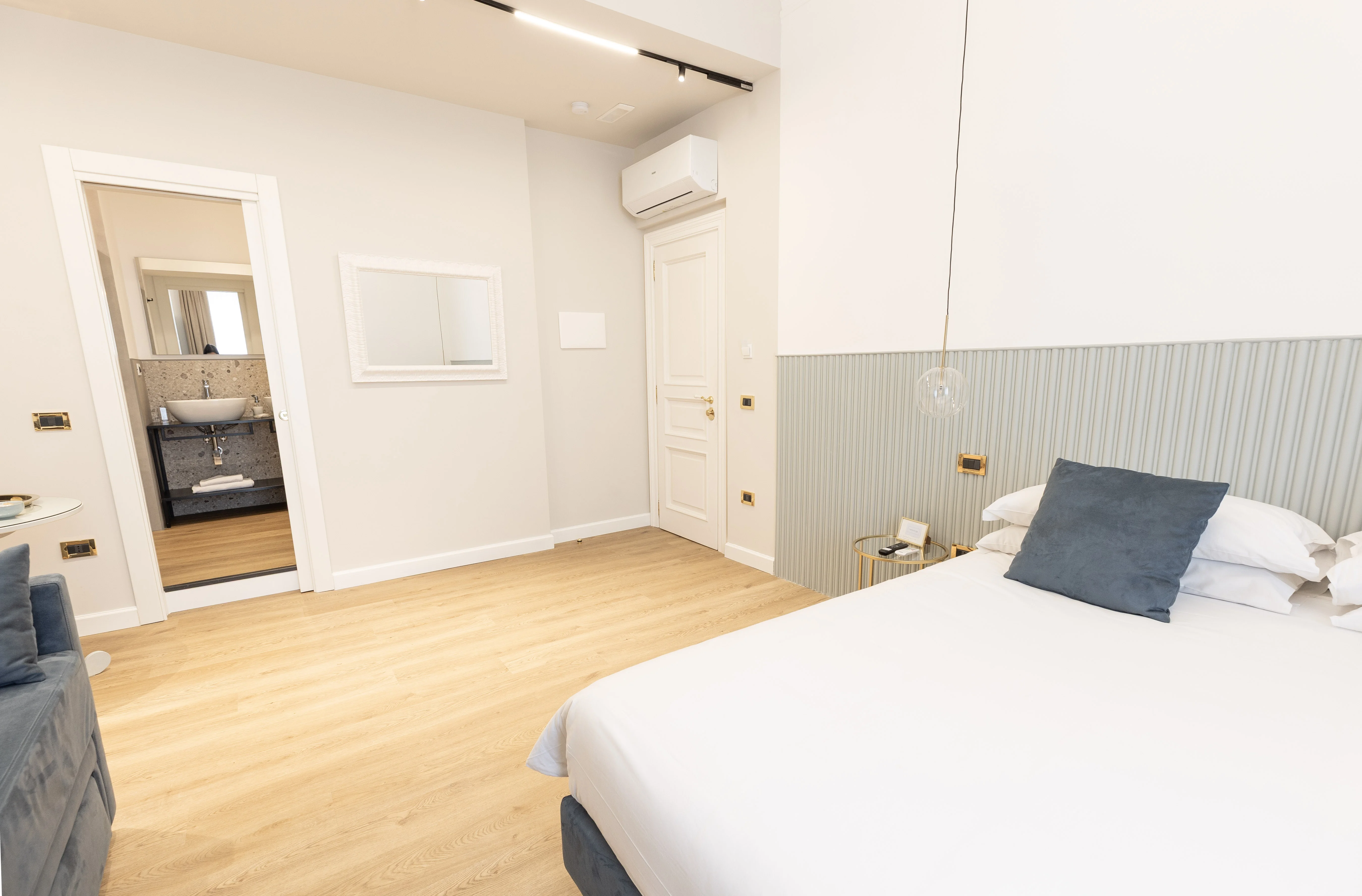 Camera Deluxe Queen — letto matrimoniale con porta del bagno aperta sul doppio lavabo