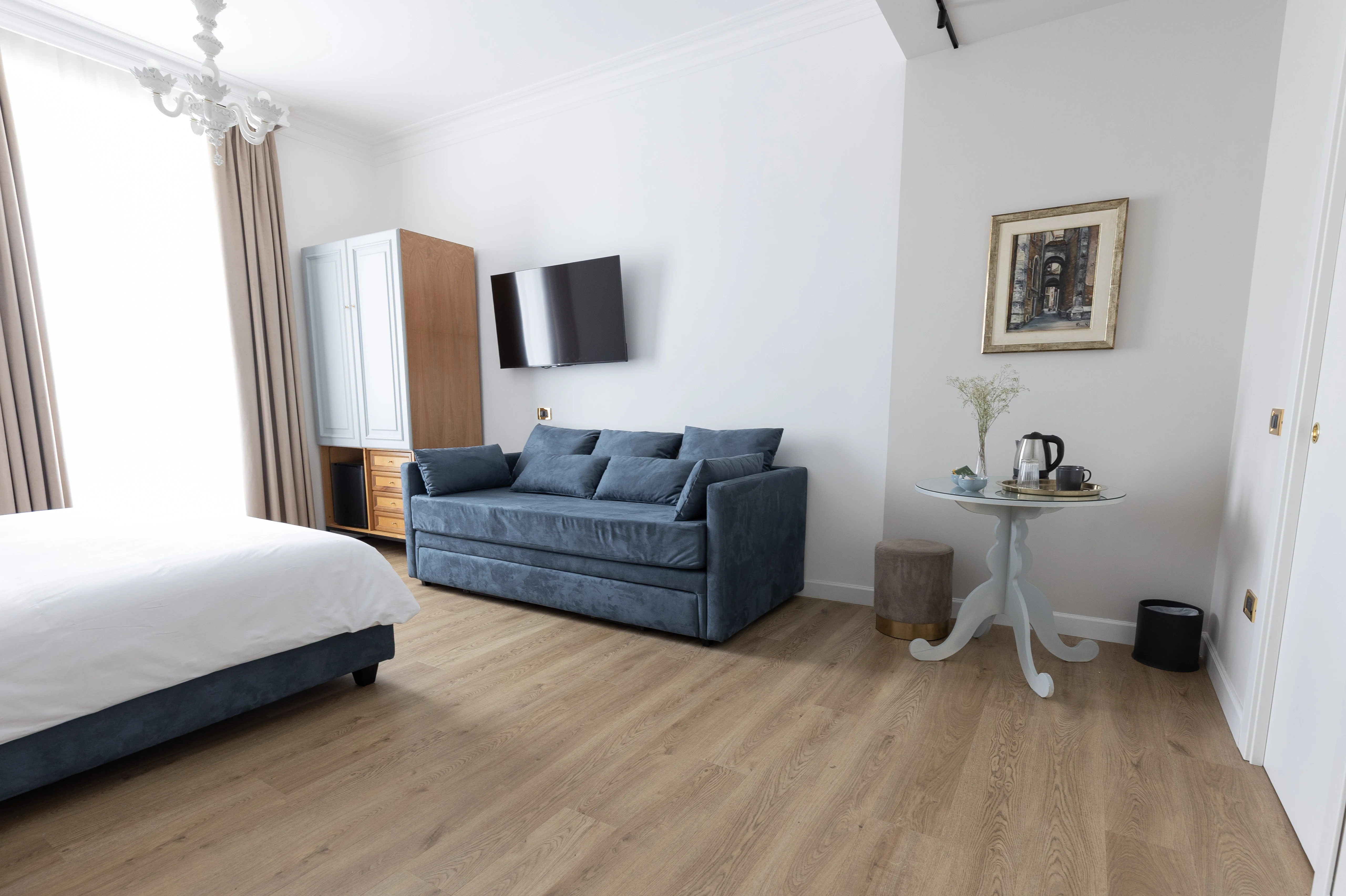 Camera Deluxe Queen — vista panoramica con divano letto, armadio e lampadario veneziano