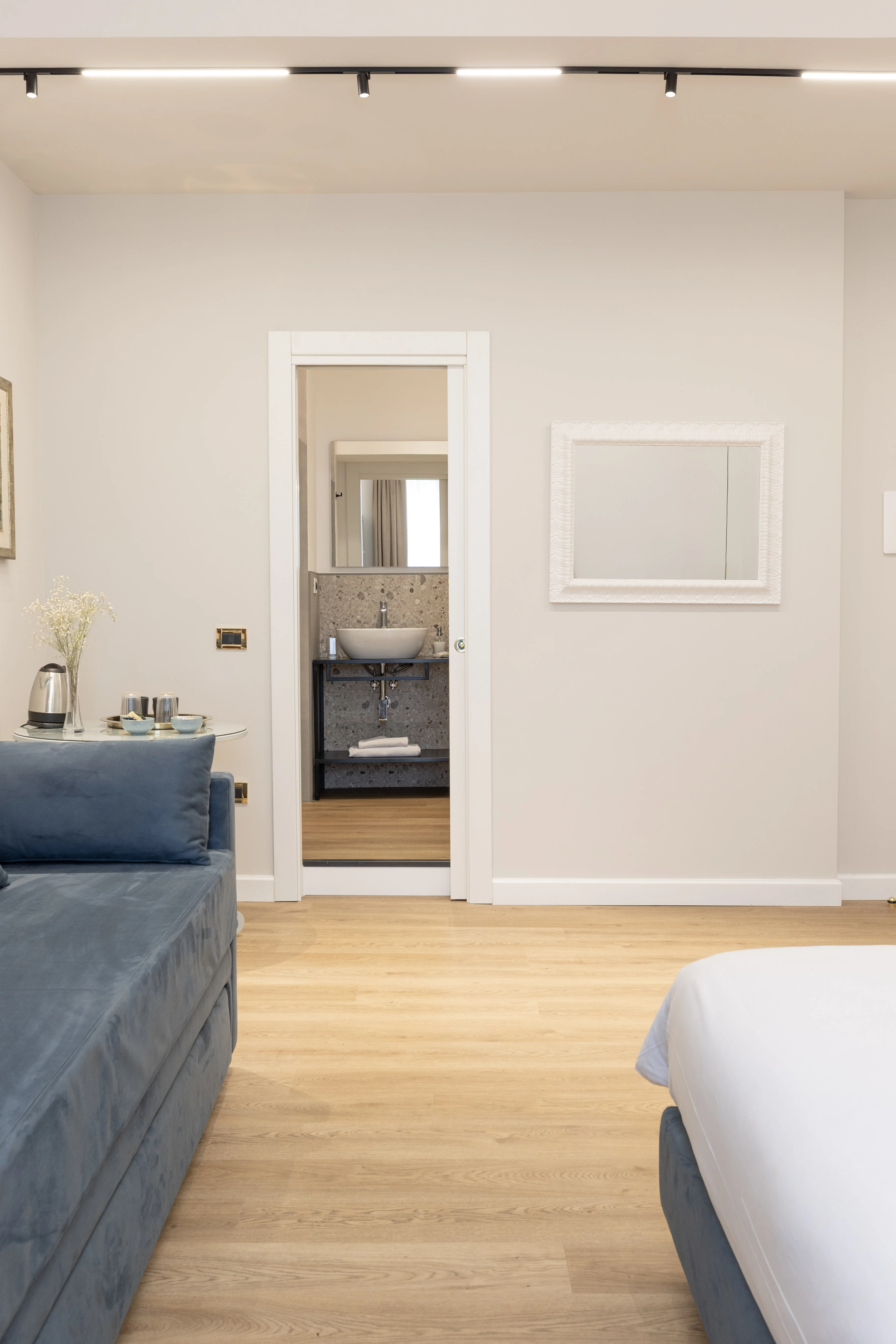 Camera Deluxe Queen — area living con divano blu in velluto e tavolino con bollitore